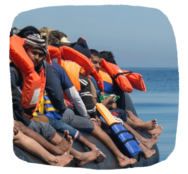 Eine Gruppe Menschen mit Rettungswesten sitzt an der Seite eines Bootes.